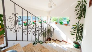 A staircase with wrought iron railings, potted plants, and a view of greenery outside. - Apartments Tapera (Dubrovnik)