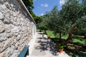 A stone wall with a bench and potted plants along a pathway. - Apartments Tapera (Dubrovnik)