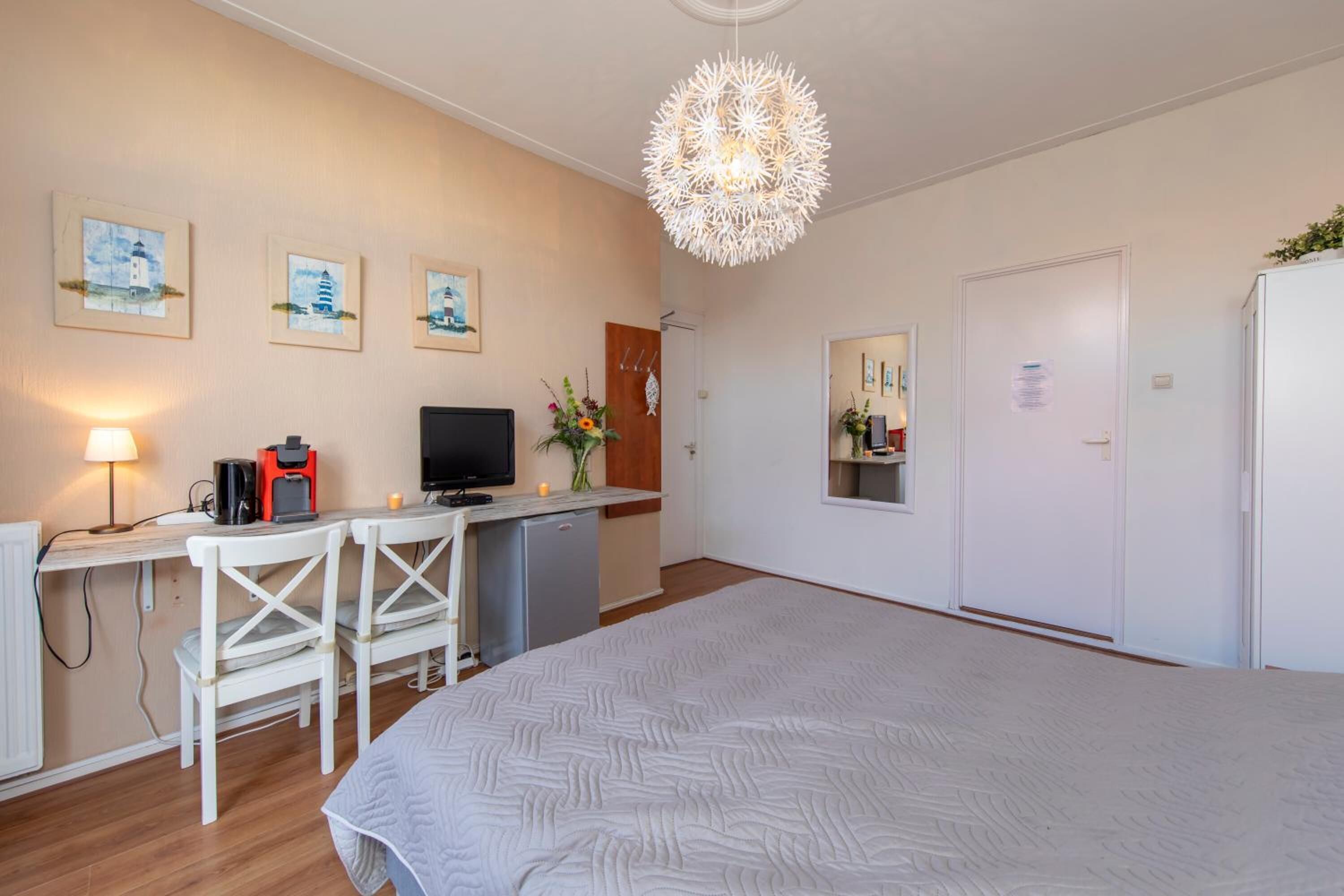 A hotel room with a bed, a desk with a TV, a coffee maker, and a small fridge.