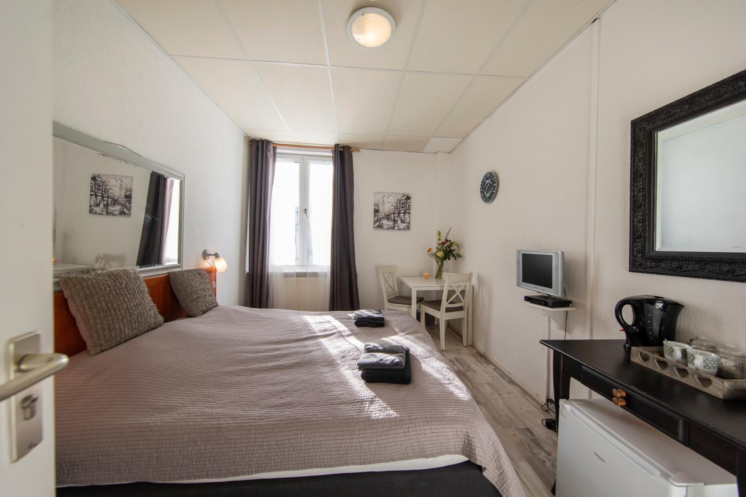 Una camera d'albergo con un letto, una scrivania, una sedia, una televisione e una macchina del caffè.