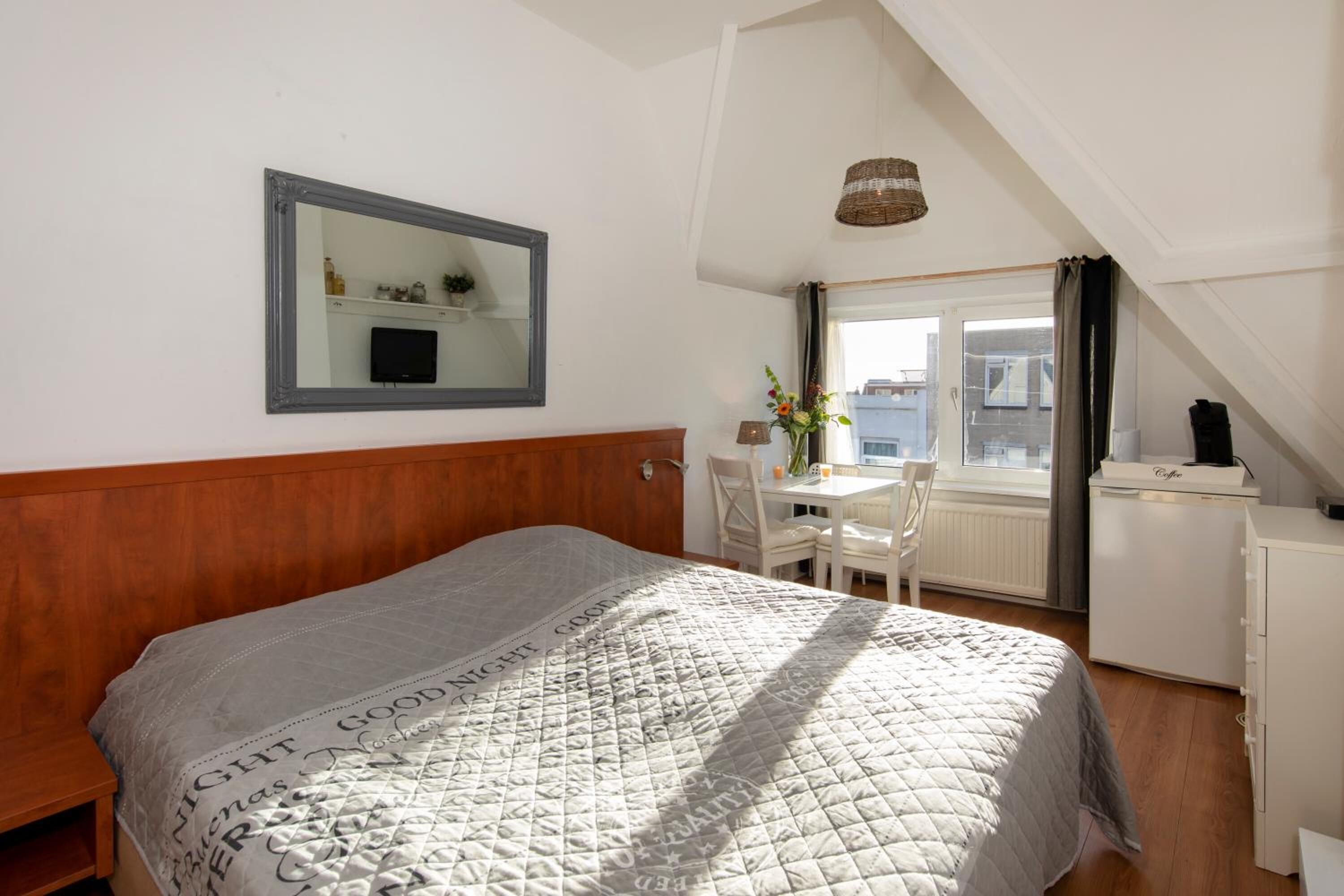 A bedroom with a bed, a desk, and a chair.