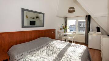 A bedroom with a bed, a desk, and a chair.