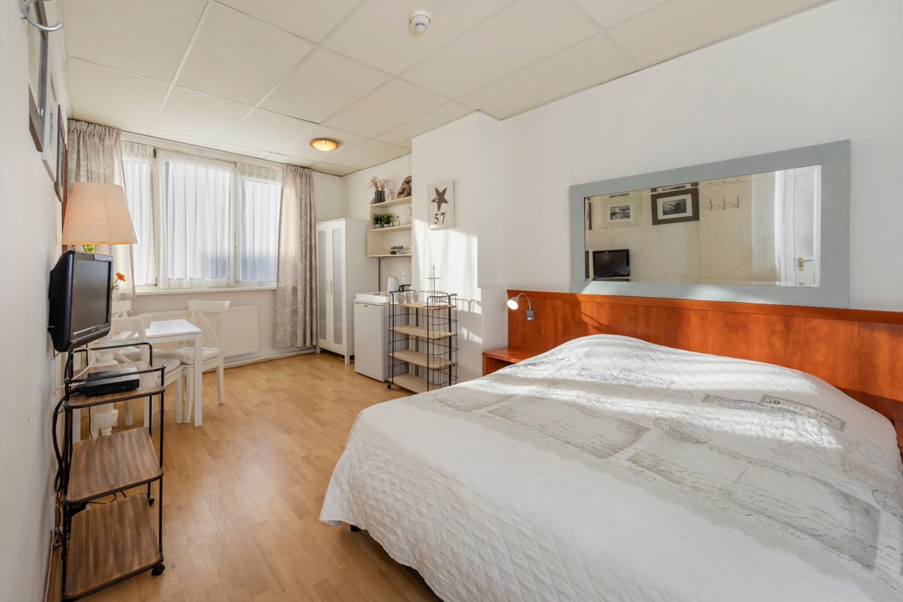 Habitación de hotel con una cama grande, un escritorio con computadora, televisor y un pequeño rincón de descanso.