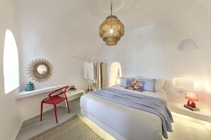 Una camera da letto con un letto, una scrivania, una sedia, un lampadario e uno specchio a parete.