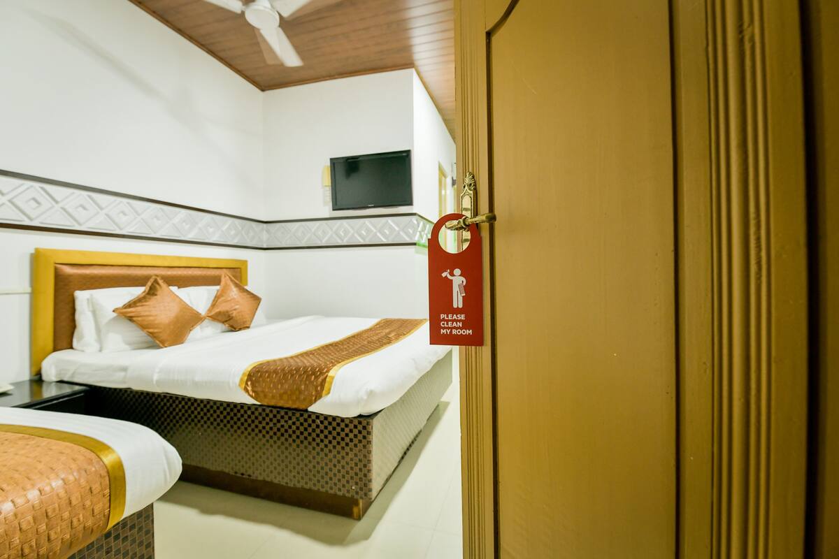A hotel room with a bed, a bedside table, and a television on the wall.