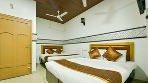 Een hotelkamer met twee bedden, een plafondventilator, een houten deur en een behangrand met een patroon.