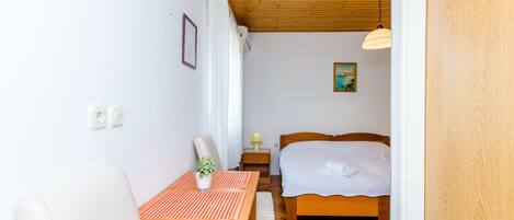 Une chambre à coucher avec un plafond en bois, un lit, une table de chevet avec une lampe et une fenêtre avec des rideaux.