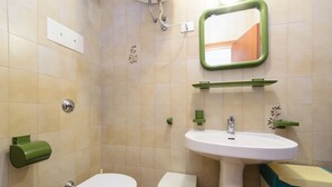 A bathroom with a toilet, sink, and mirror. - Condominio Sabbiadoro (Lignano Sabbiadoro)