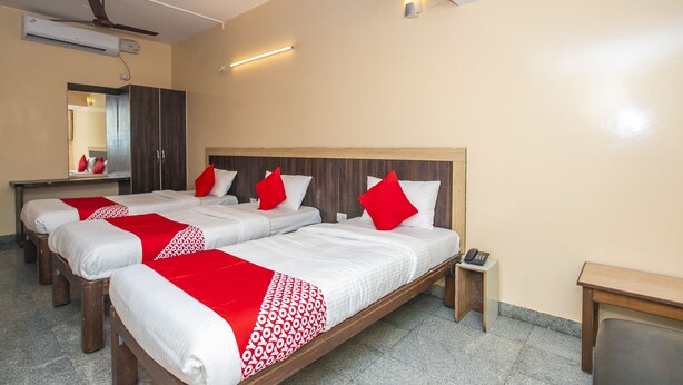 Habitación de hotel con dos camas, un escritorio, un espejo y un ventilador de techo.