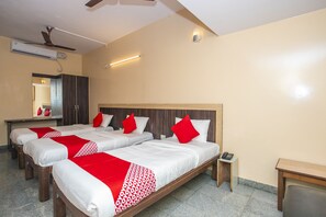 A hotel room with two beds, a desk, a mirror, and a ceiling fan. - OYO 12965 Archana Comforts (Bengaluru)