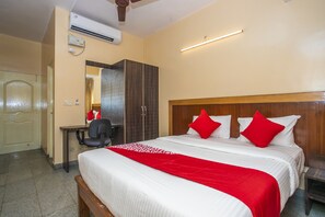 A hotel room with a bed, a desk, a chair, and a wardrobe. - OYO 12965 Archana Comforts (Bengaluru)