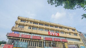 Un edificio de varios pisos con varios rótulos comerciales, incluyendo un llamativo letrero de 'OYO' en el piso superior.