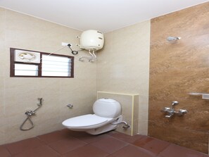 Une petite salle de bain avec des toilettes, une douche et une fenêtre.