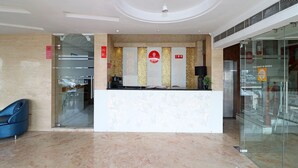 Ein Hotel-Empfangsbereich mit Marmorboden, einer Rezeption und einer Glaswand.