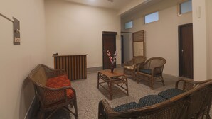 Un salón espacioso con muebles de mimbre, una mesita con un jarrón y un ventilador de techo.