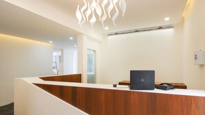 A reception desk with a wooden finish, a Dell laptop, and a telephone.