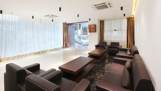 A modern hotel room with a seating area, large windows, and a view of the street.