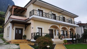 A two-story hotel with a balcony, a front entrance, and a garden area. - Gogos Hotel (Kalabaka)