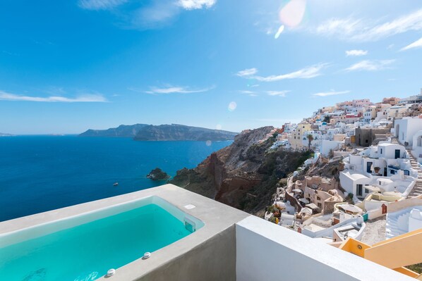 A coastal view with a swimming pool, white buildings, and a clear blue sea. - Big Blue Villa by Caldera Houses (Santorini)
