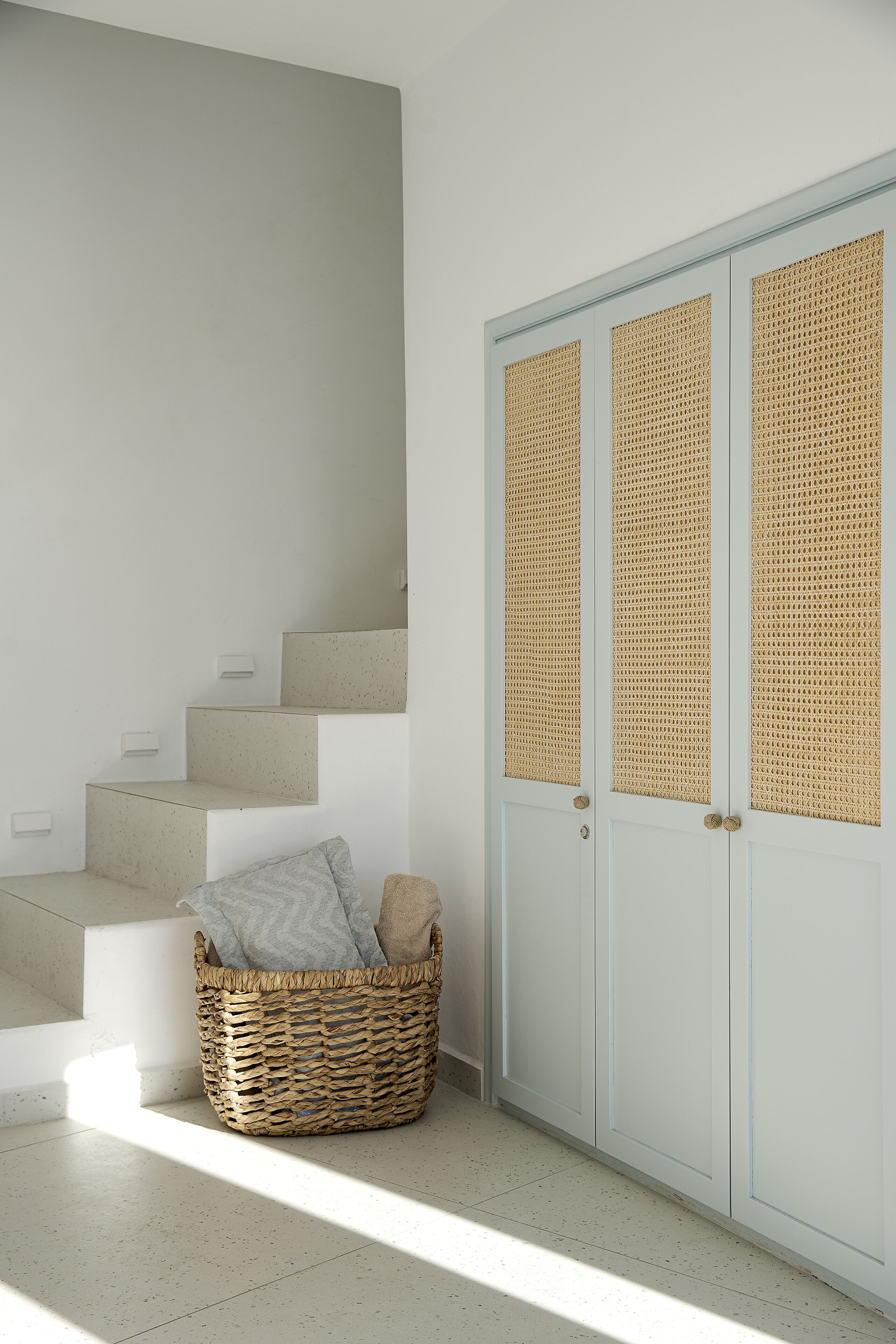 A staircase leading to a room with a white door featuring woven panels.