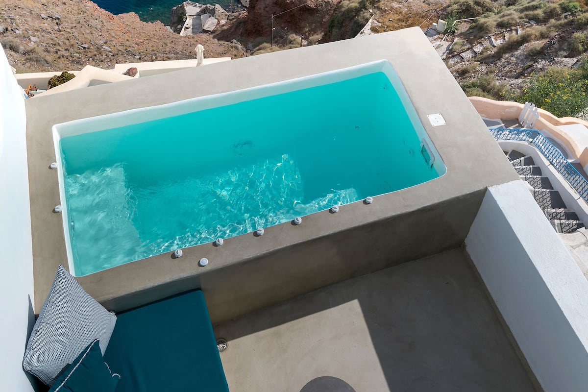 Piscina infinita en la azotea con vista al mar y al paisaje rocoso.