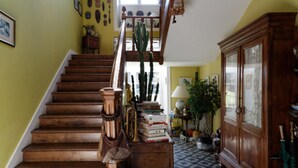A wooden staircase with a brass handrail, a cactus, and books on a side table.