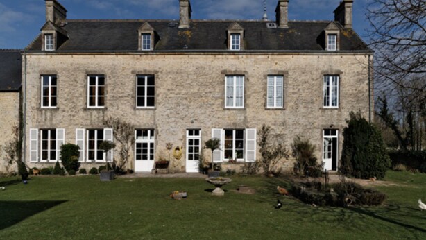 A stone building with multiple windows and a well-maintained lawn.