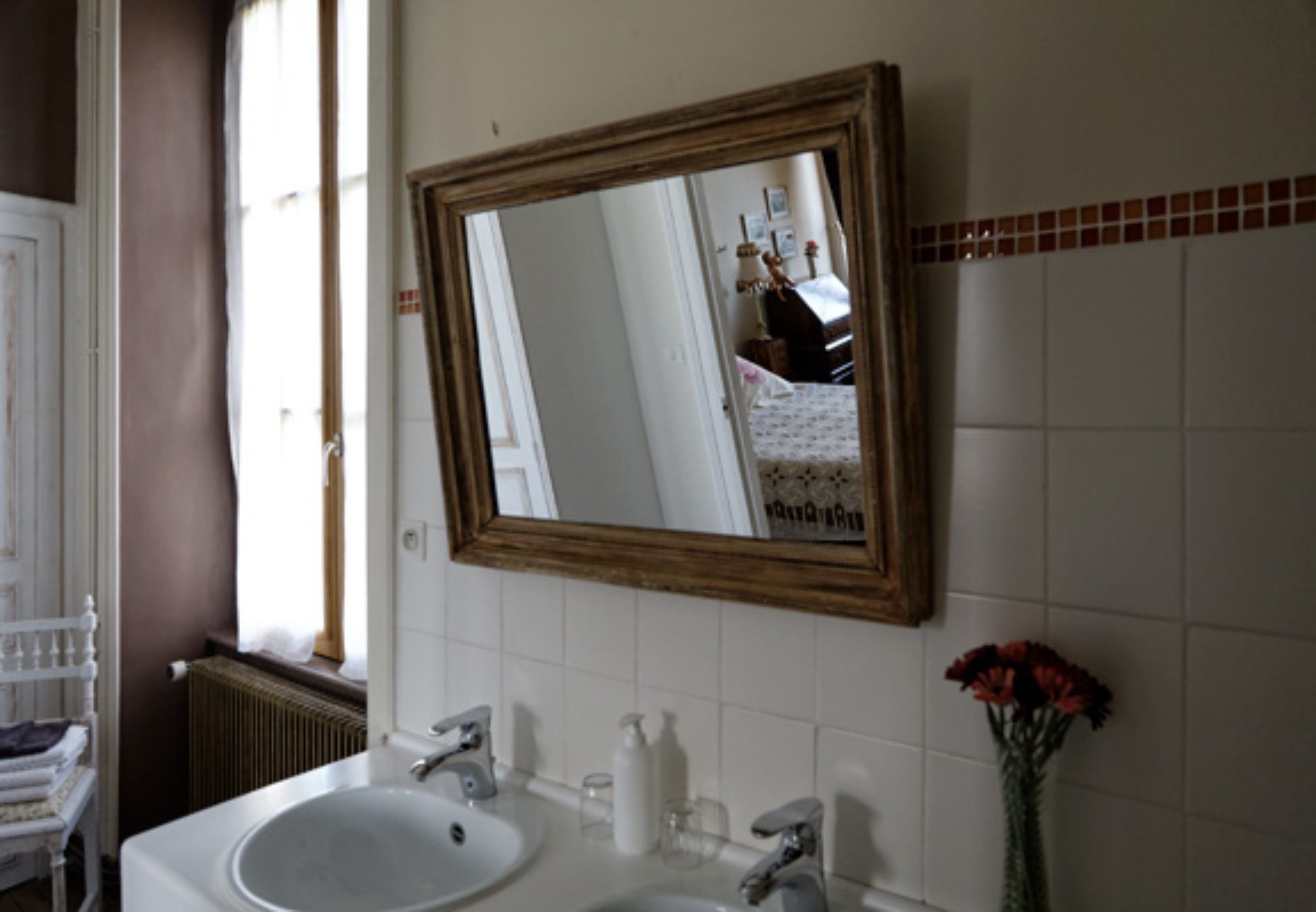 Un baño con un espejo grande, dos lavamanos y un radiador.