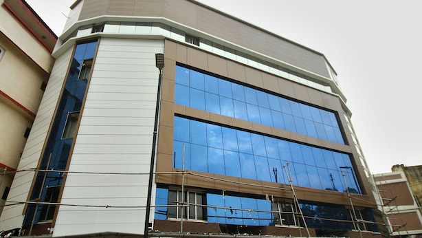A modern building with a corner entrance, large reflective windows, and a flat roof. - OYO 19910 Hotel Sapphire Paradise (Ooty)