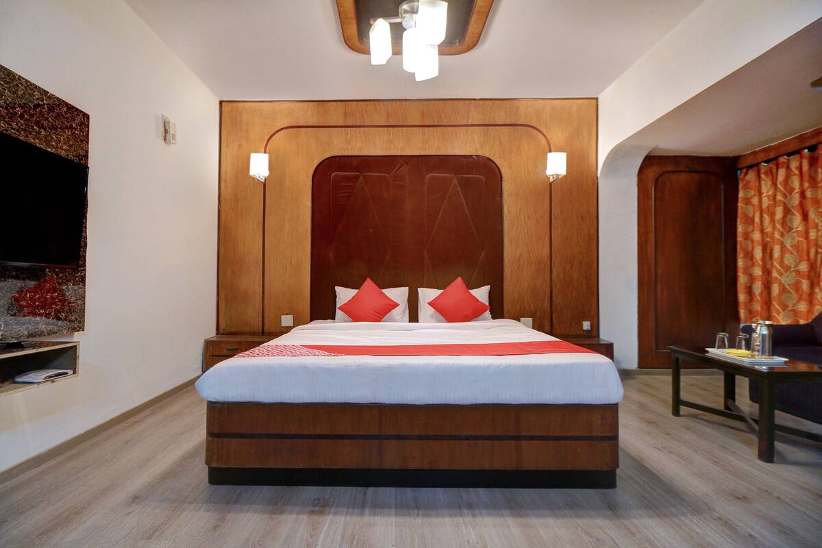 Ein Hotelzimmer mit einem großen Bett, einem Holzkopfende und einem kleinen Tisch mit Stuhl.