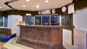 A reception area with a marble counter, framed pictures, a clock, and a calendar on the wall. - OYO 19910 Hotel Sapphire Paradise (Ooty)