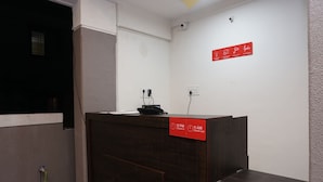 Ein Empfangsschalter mit Schildern für Check-in und Check-out, ein Telefon und ein an der Wand befestigtes Schild mit Notfallhinweisen.