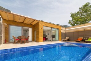 Una piscina al aire libre, sillones reclinables de piscina