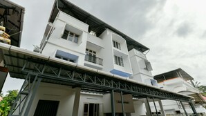 A multi-story building with a flat roof and a covered walkway. - OYO 18602 Home Spacious Stay Near Lulu Mall (Kanayannur)