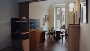 Een moderne keuken met houten keukenkastjes, een inbouwoven en een eethoek met een ronde tafel en stoelen.