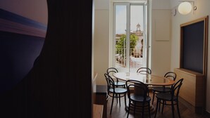 Een eetgedeelte met een ronde tafel en stoelen, een uitzicht op een gebouw met een klokkentoren en een groot raam.