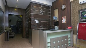 A hotel reception area with a reception desk, a clock, a fan, and a sign indicating outside food is not allowed. - OYO 19334 Flagship Shanta Inn Charbagh (Lucknow)