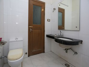 A bathroom with a toilet, sink, mirror, and tiled walls. - OYO 19334 Flagship Shanta Inn Charbagh (Lucknow)