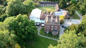 An aerial view of a large, historic building with multiple sections, surrounded by lush greenery and a well-maintained lawn. - Mulberry House (Ongar)