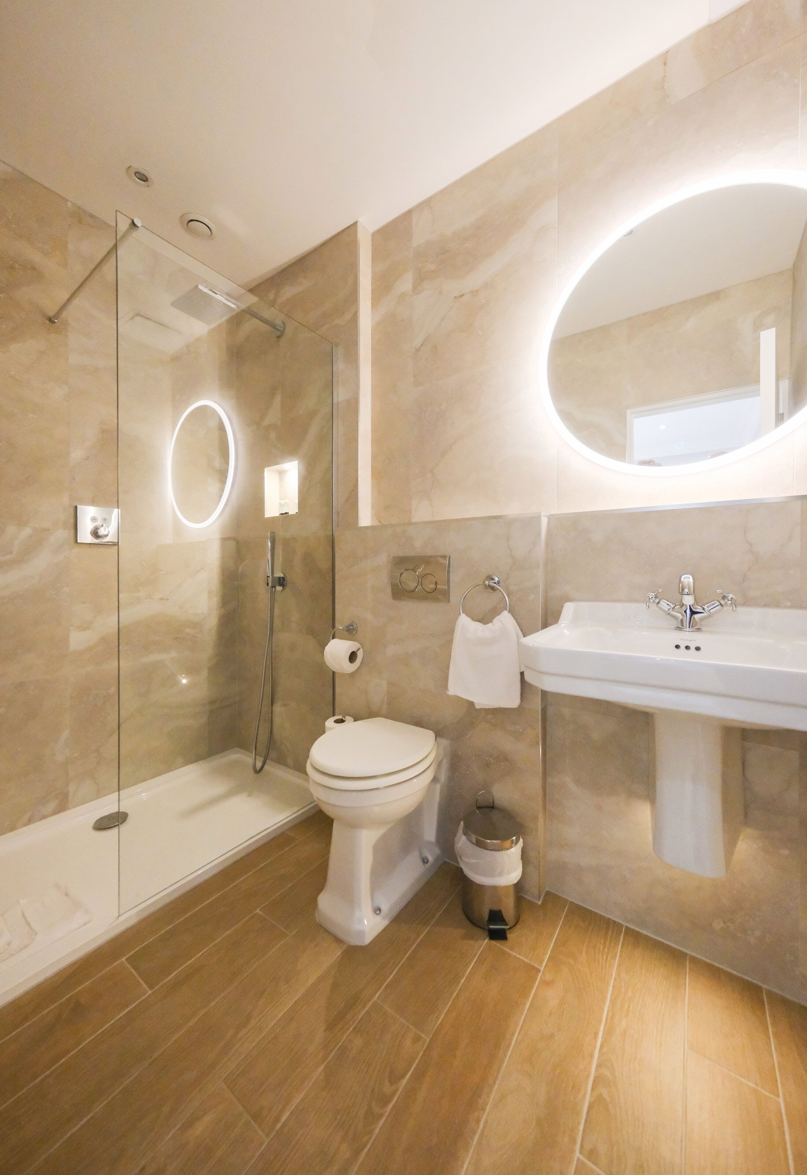 A modern bathroom with a glass-enclosed shower, a toilet, and a sink with a mirror.