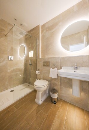 A modern bathroom with a glass-enclosed shower, a toilet, and a sink with a mirror. - Mulberry House (Ongar)