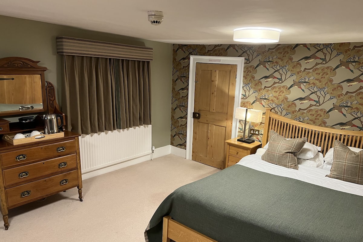 A bedroom with a bed, wooden dresser, and a door with a sign.