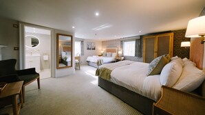 A hotel room with a large bed, a desk, a chair, a mirror, and a bathroom visible through an open door. - Mulberry House (Ongar)