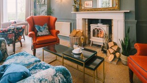 A cozy living room with a fireplace, a large mirror, and comfortable seating. - Mulberry House (Ongar)