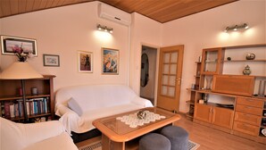 Un salon confortable avec un canapé, une table basse, une bibliothèque et une porte donnant sur une autre pièce.