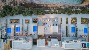 Vista aérea de un moderno complejo turístico con varias piscinas, tumbonas y una zona de playa.