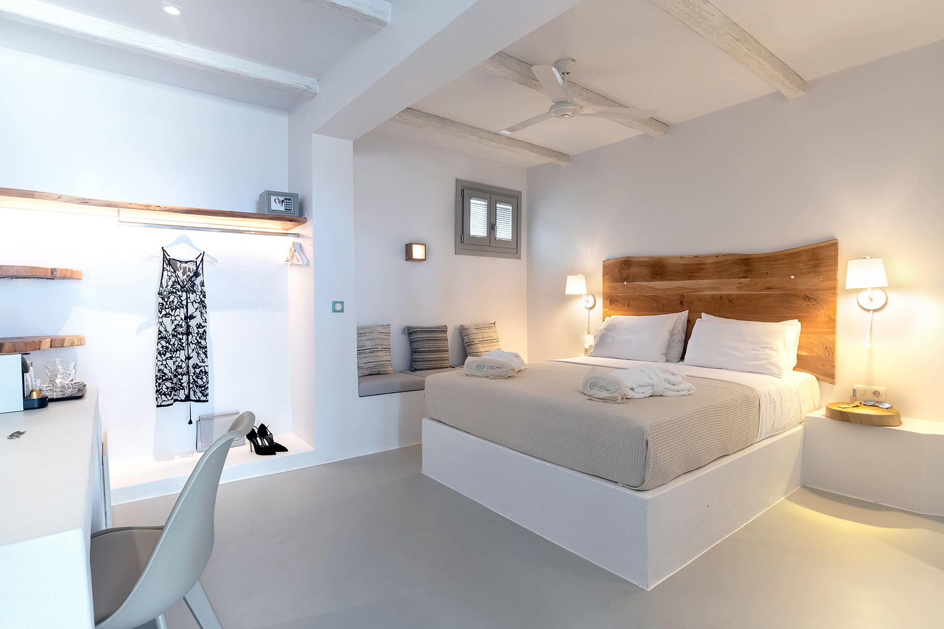 A modern bedroom with a large bed, bedside lamps, a ceiling fan, and a window with blinds.