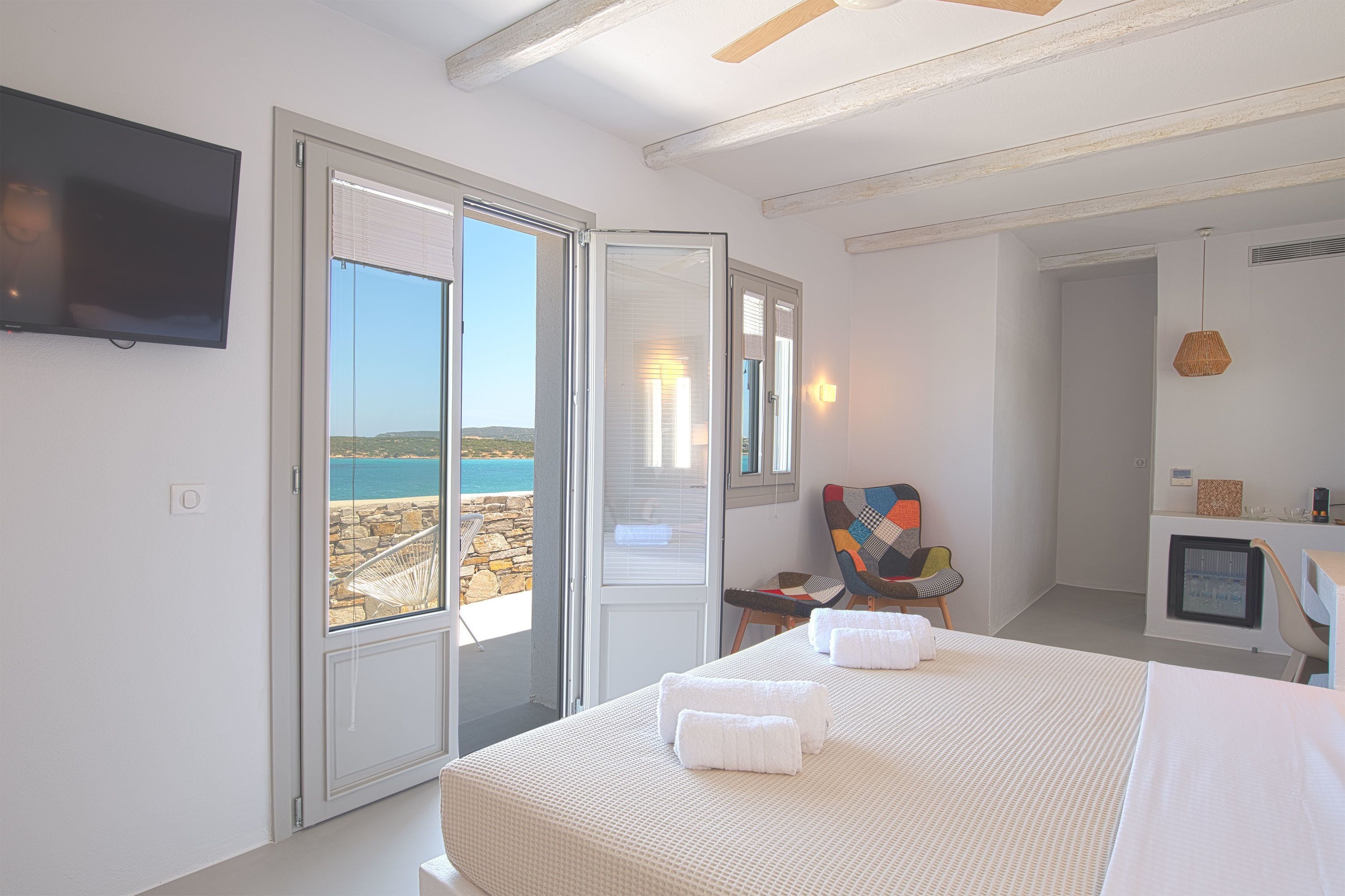 Una habitación de hotel con una cama, televisor, silla y escritorio con computadora.