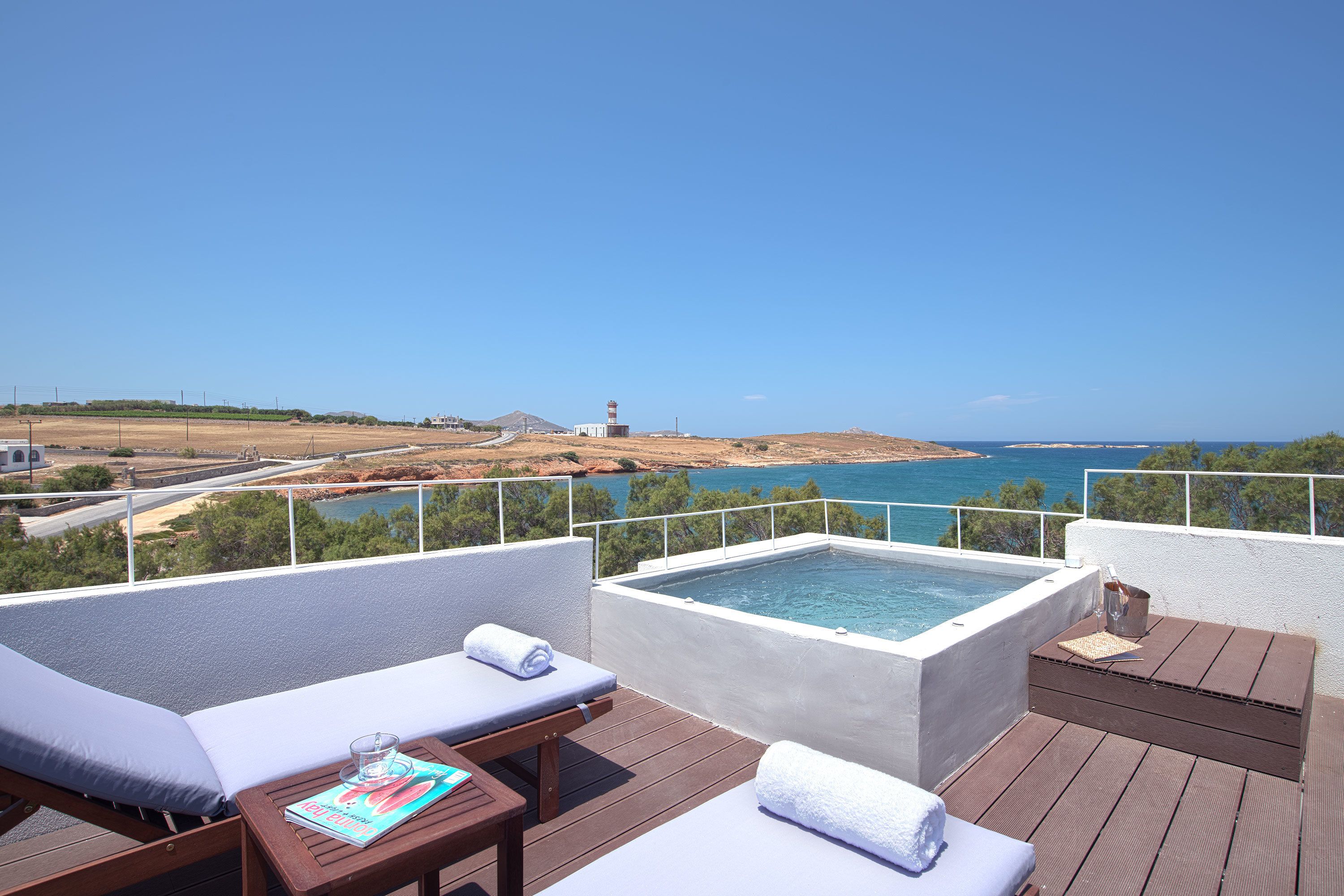 A rooftop terrace with a hot tub, lounge chairs, and a view of the sea.
