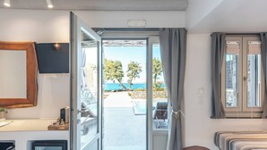 Una habitación con puerta corrediza de vidrio que da a un espacio exterior con piscina y vista al mar.
